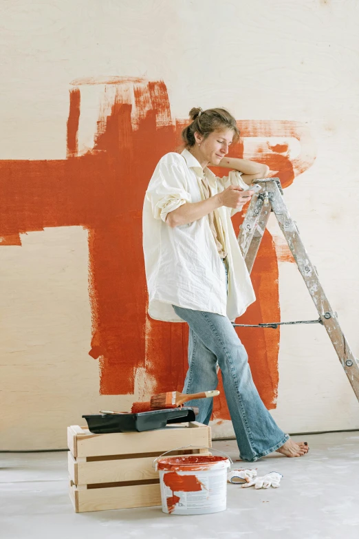 the woman is painting a wall on the side of her house