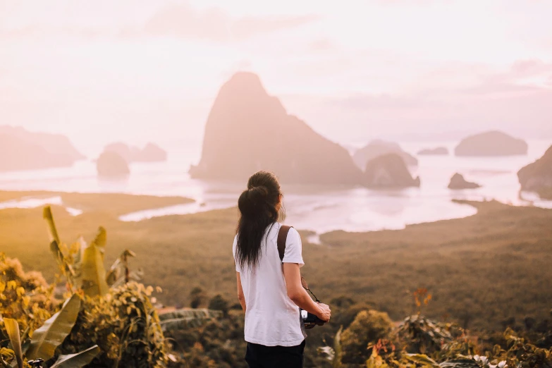 a person on a hill overlooking a bay and some mountains