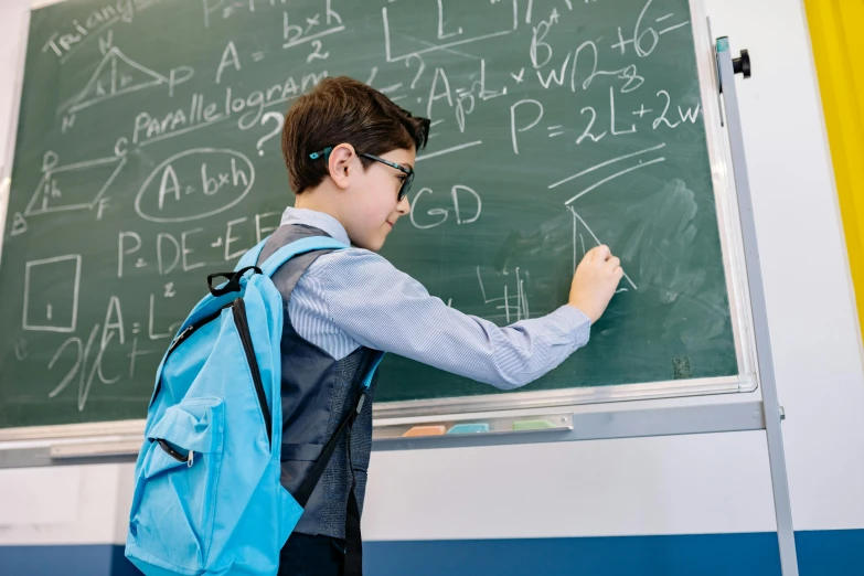 the boy is learning in a school at blackboard