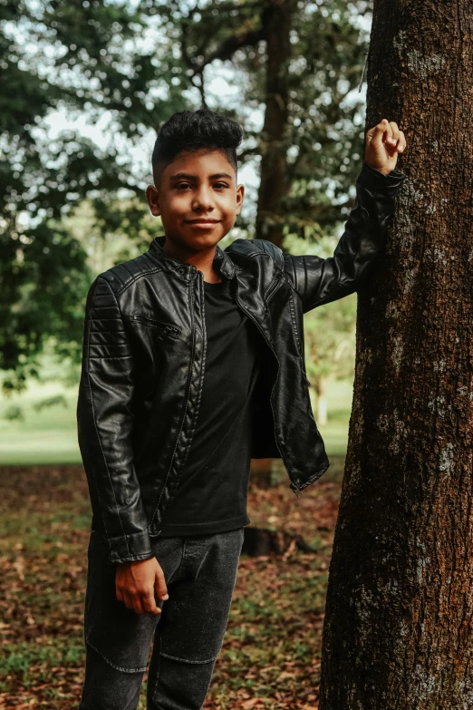 an image of a young man leaning up against the tree