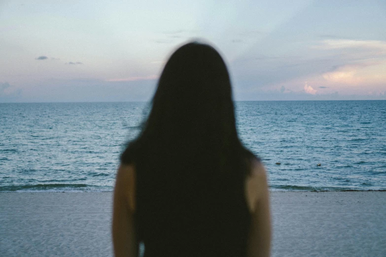 a woman standing on the beach looking out over the ocean