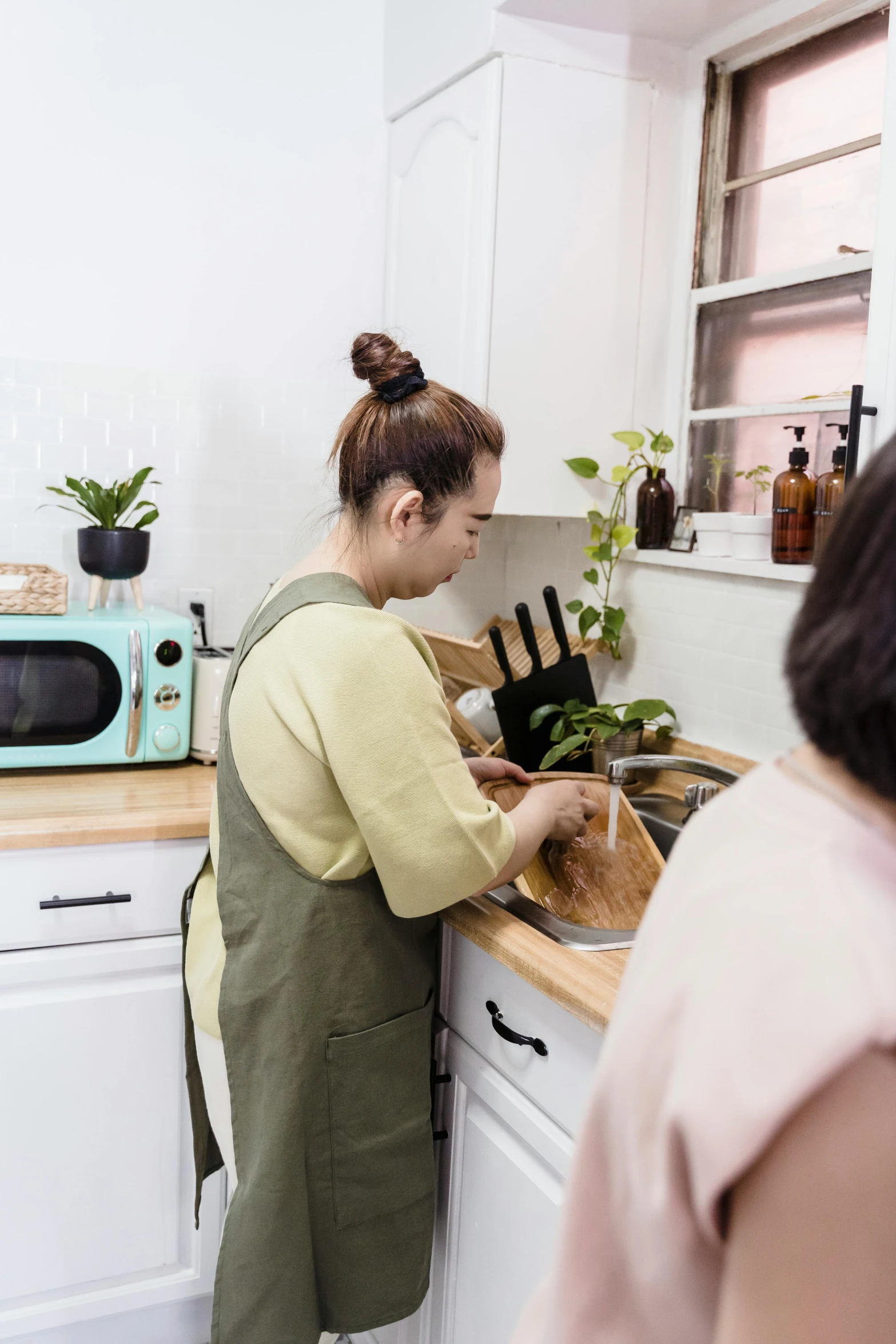 a woman in the kitchen with plants inside