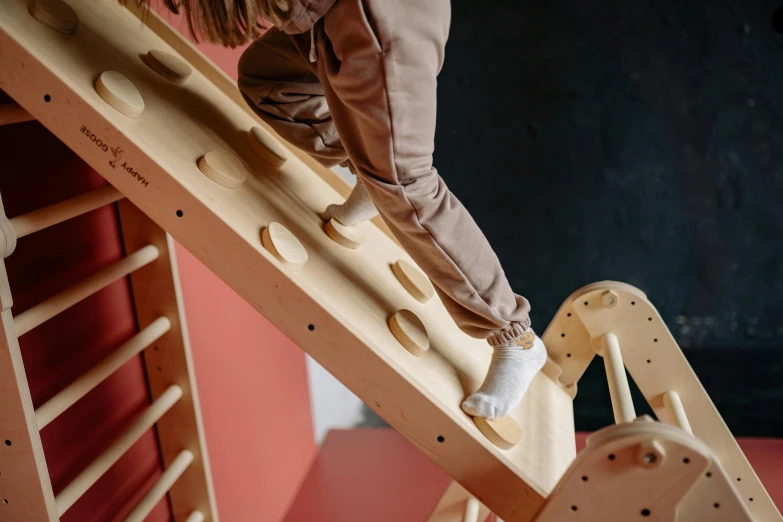 a child's wooden toy climbing down to the top of a ladder