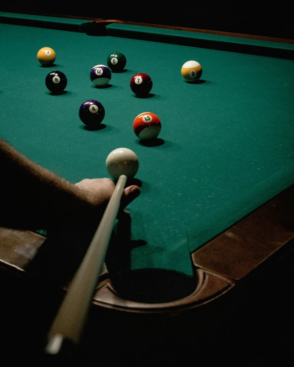 man playing pool in dark room with billiard table and balls