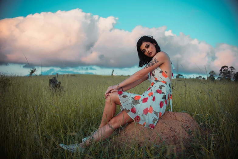 a woman in an adorable dress sitting on top of a rock
