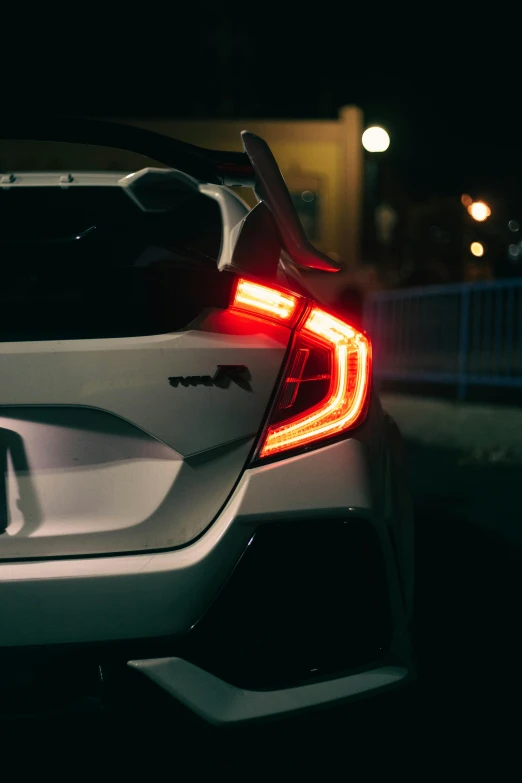 the rear end of a white car at night