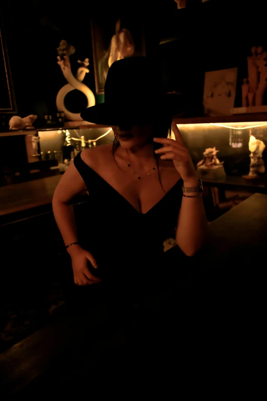 a woman in a black dress and hat standing in front of a bar