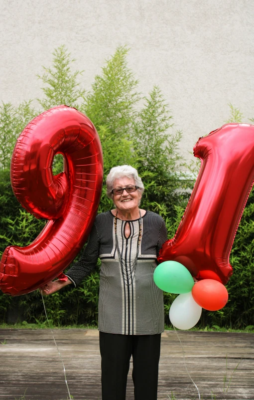 an older woman holding red and green balloons