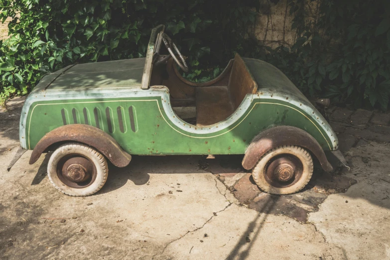 an old, rusty looking car sitting on concrete