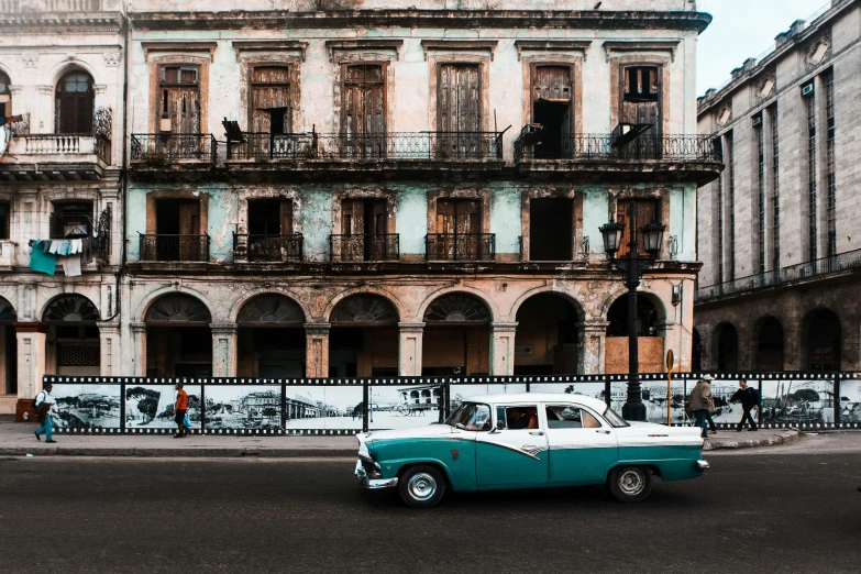 a vintage car is parked by a building on the street