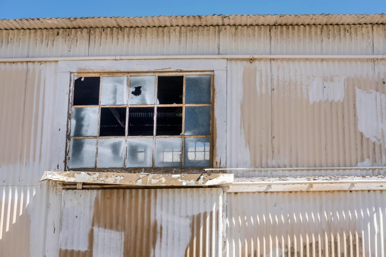 an open window with bars of glass on a white brick wall