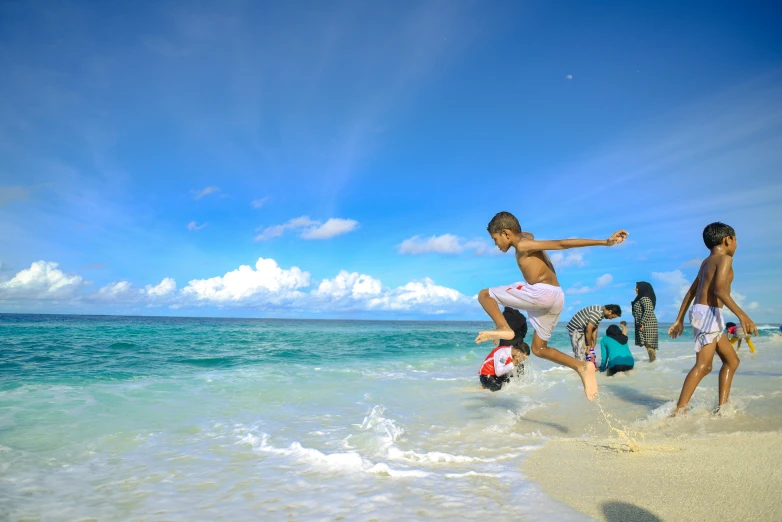 people playing on the beach with blue skies and ocean