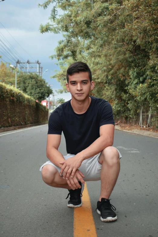 a man crouches down on the side of the road to pose for a po