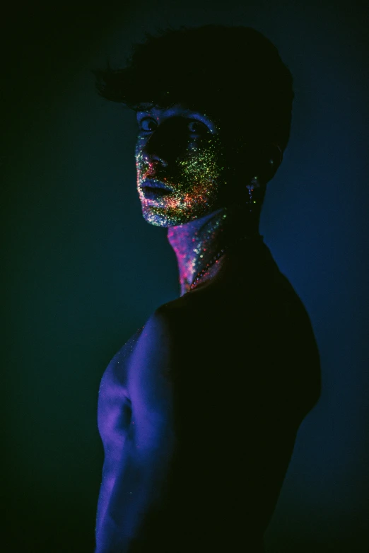 a man with hologise body paint standing in the dark