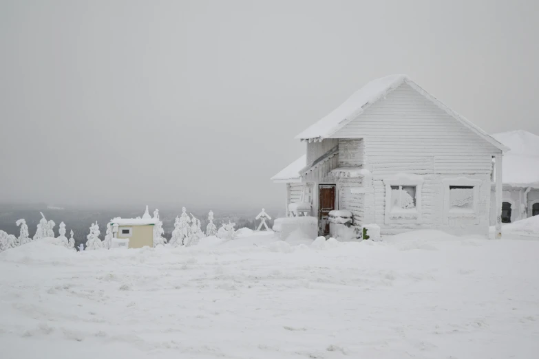 white house covered in snow sitting next to the ocean