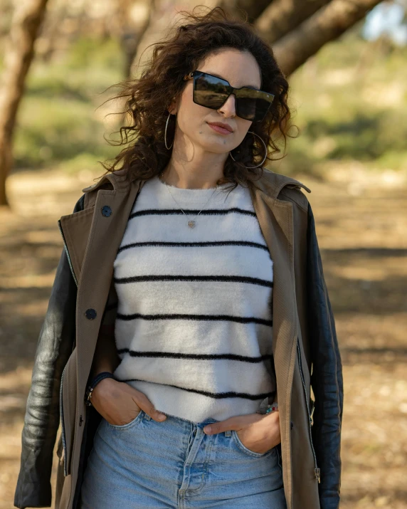 a woman with sunglasses on is standing in the grass