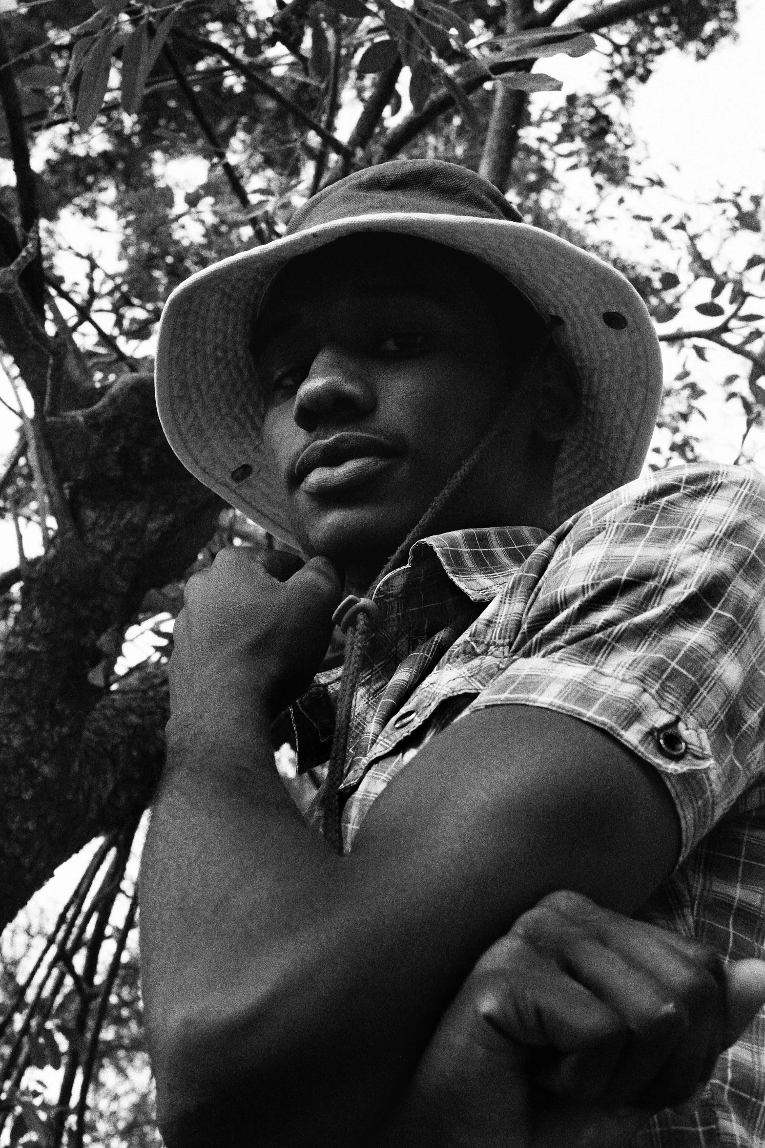 a man wearing a hat standing in front of trees