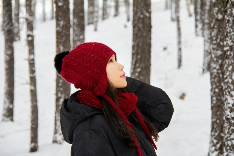 woman in red hat standing in snow next to a tree