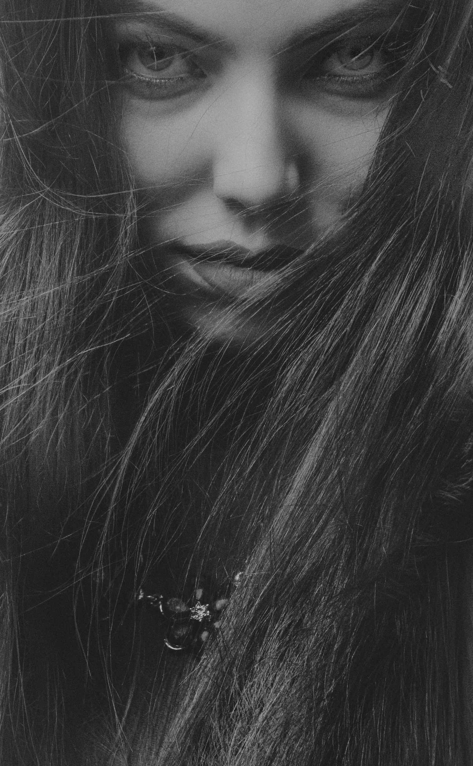 black and white pograph of a young woman's face with her hair flying in the wind