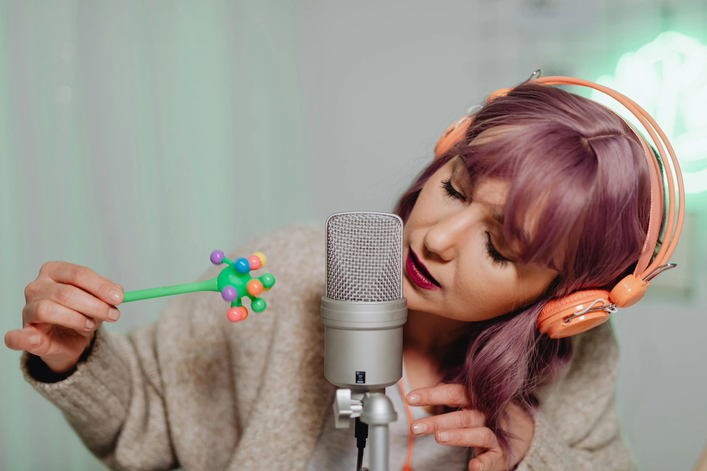 a woman with pink hair holds an object to her face