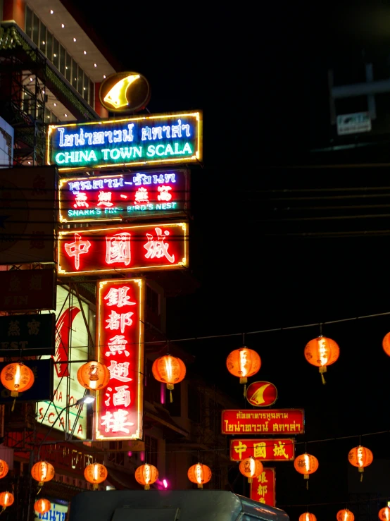 a large chinese sign and red lanterns hanging over the road