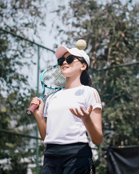 a woman wearing a hat and sun glasses holds a tennis racket