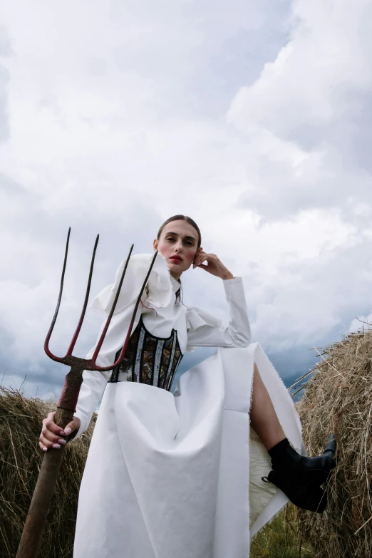 a woman in a long white dress sitting on some hay