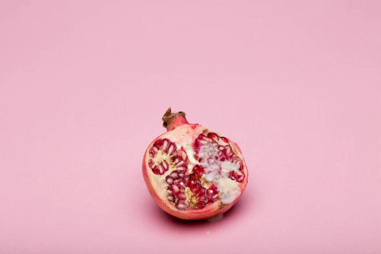 a pomegranate on a pink background with other fruit