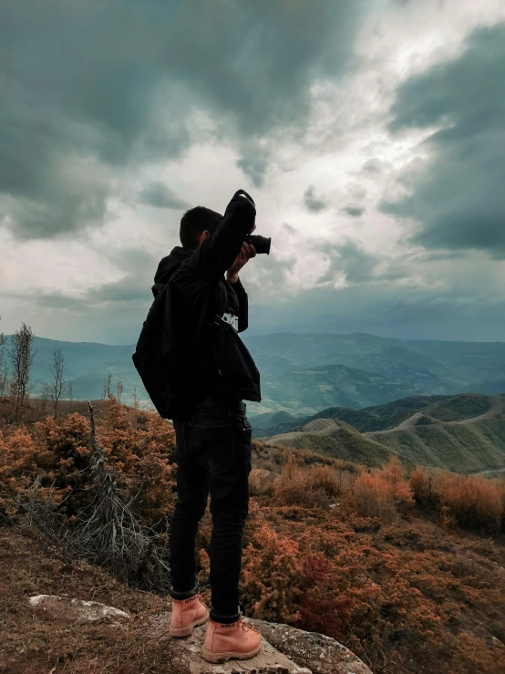 man taking picture of a scenic view from a high mountain