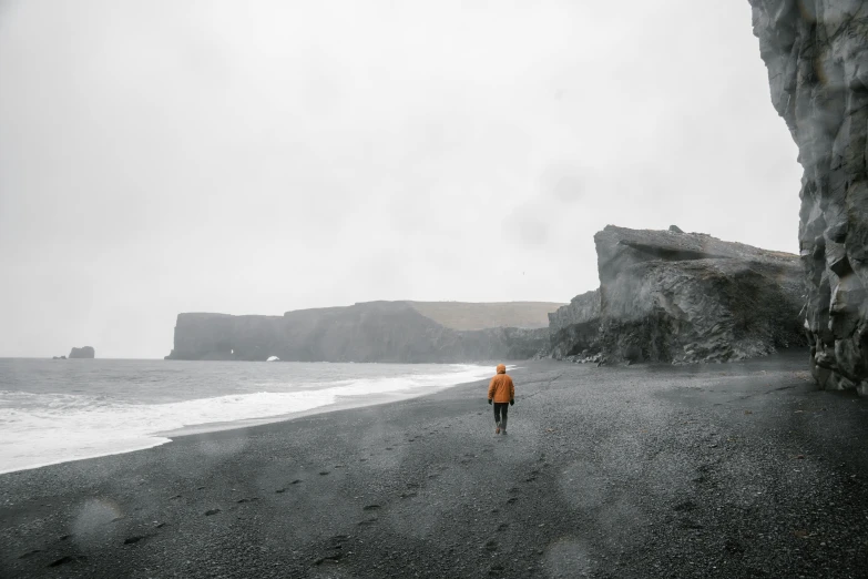 the lone person is walking on the wet sandy beach