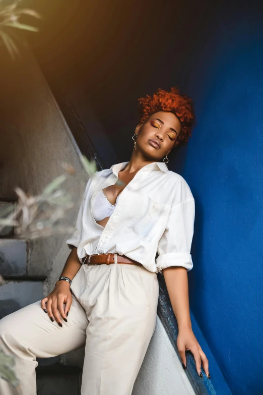 a woman with red hair is leaning against a wall