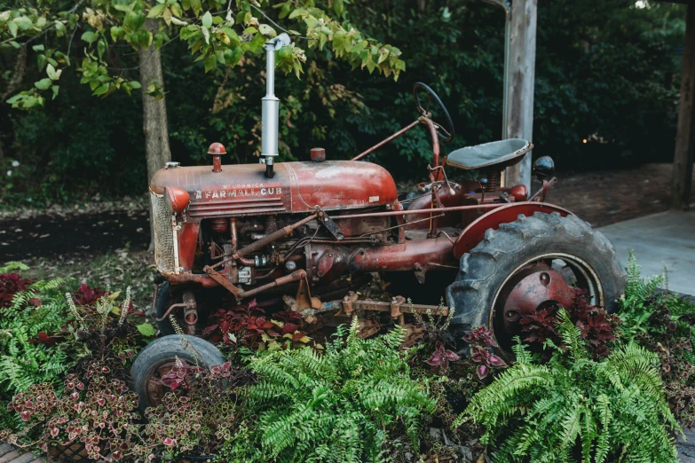 an old red farmall tractor is parked by the curb