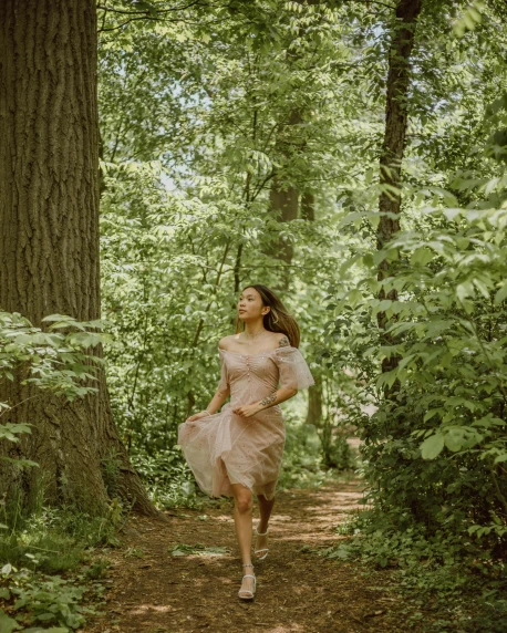 a woman in pink dress walking in the woods