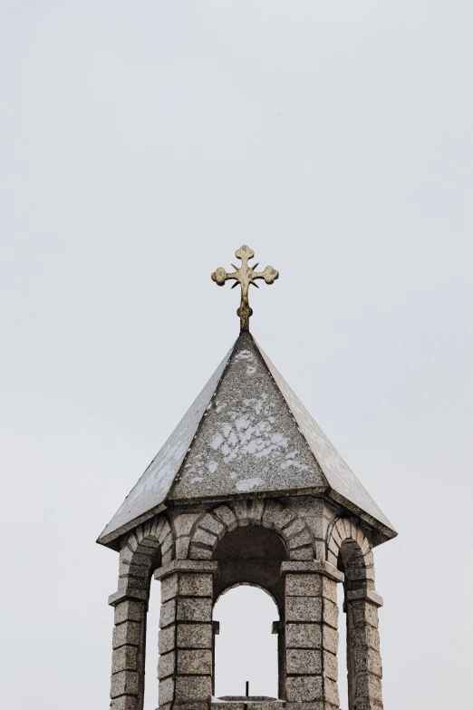 the clock tower has a metal cross on top of it