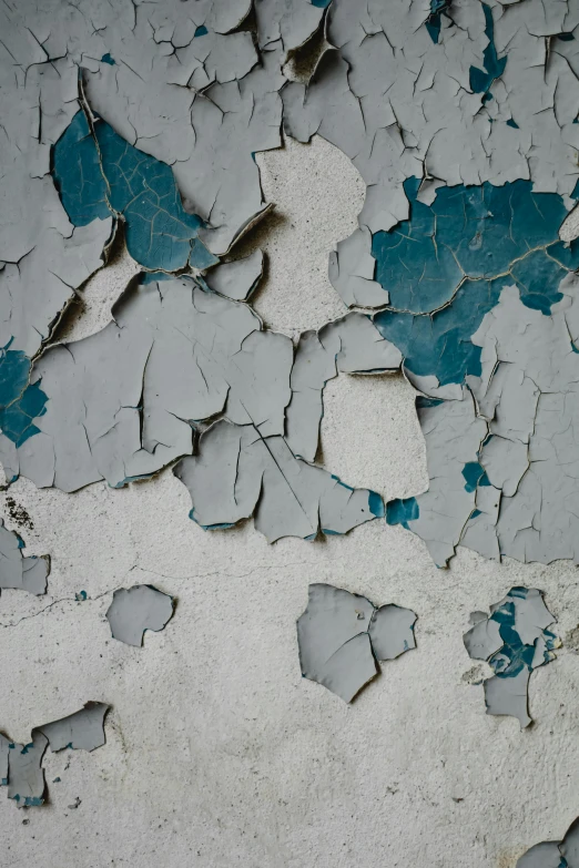 a peeling, chipped wall is covered in light blue paint