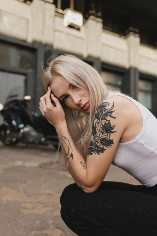 woman with full body tattoos sitting next to motorcycle