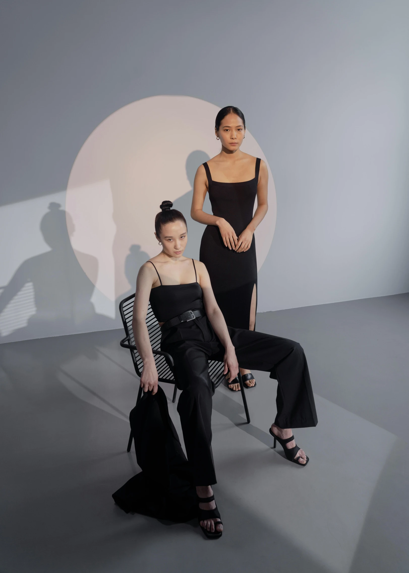 two woman sitting next to each other wearing black dresses