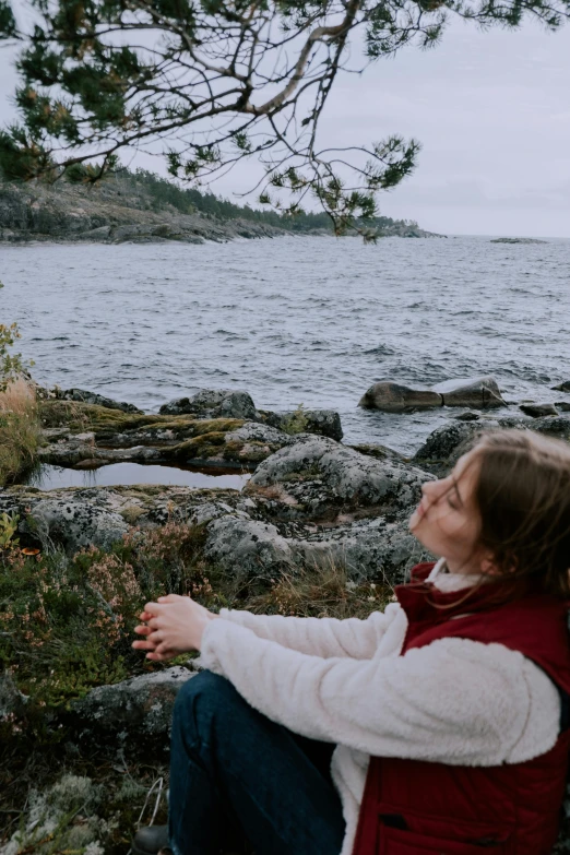 woman sitting on rocks looking at an animal by the water