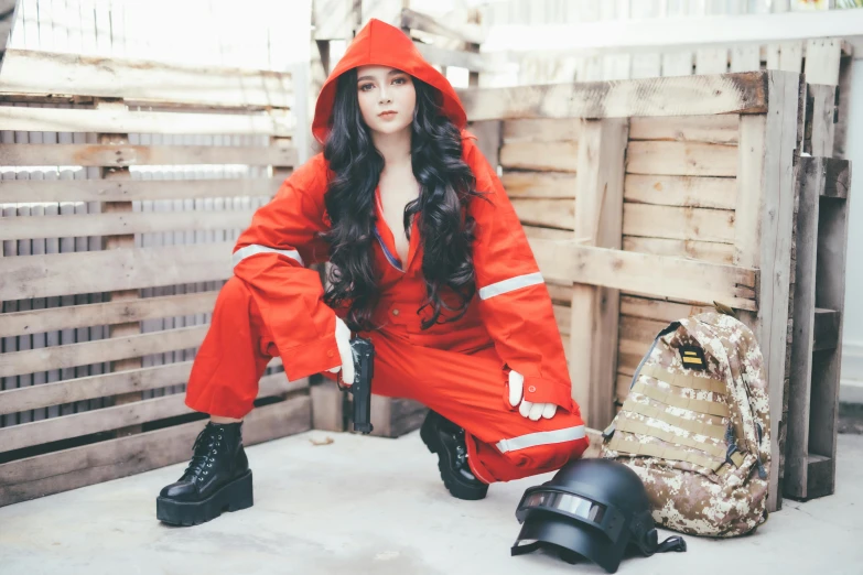 a woman in an orange rain suit squatting on a wooden slatt