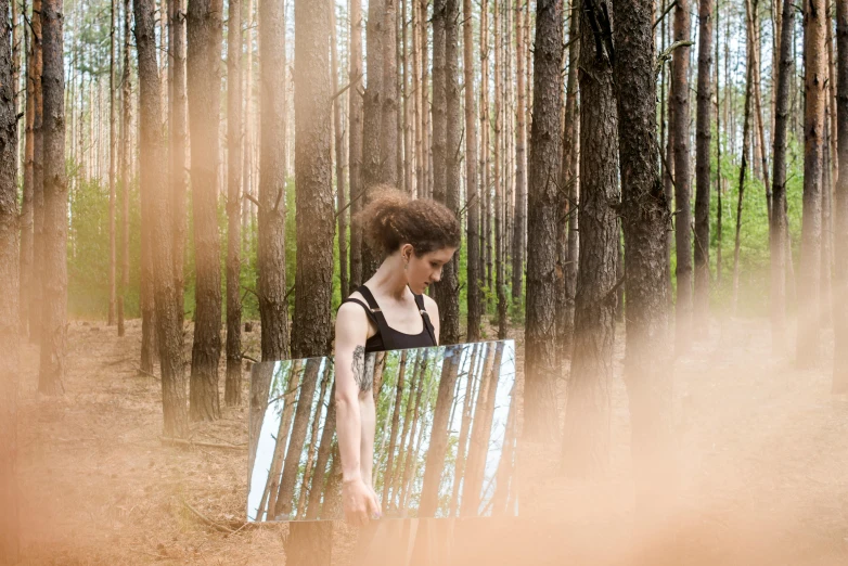 the girl is standing in the forest near a bench