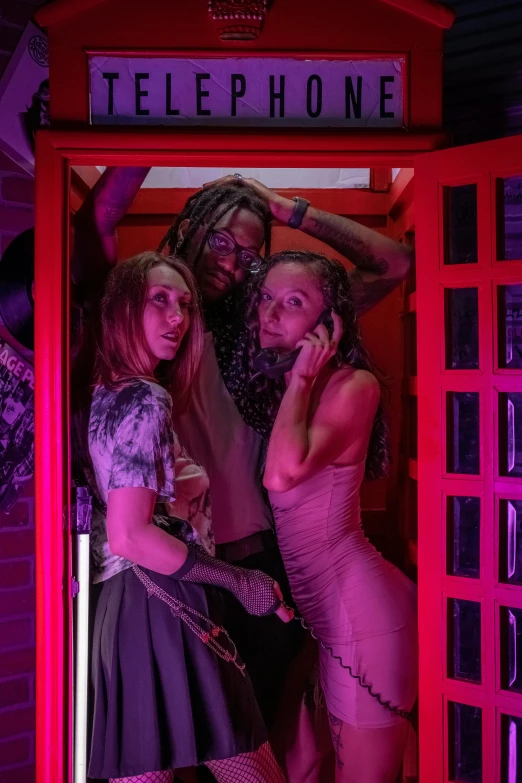 three woman in dresses inside a telephone booth
