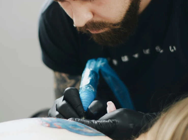 a man getting a tattoo from another person
