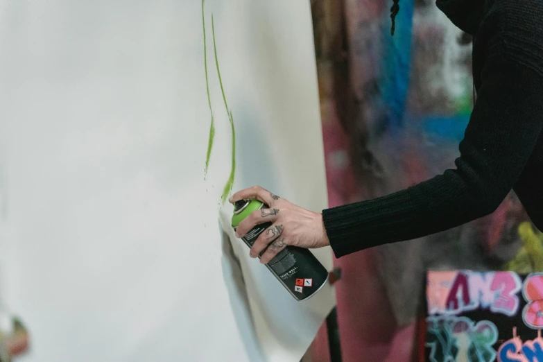 a person spray painting a wall with green paint