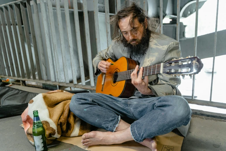 a man sitting down playing an orange guitar