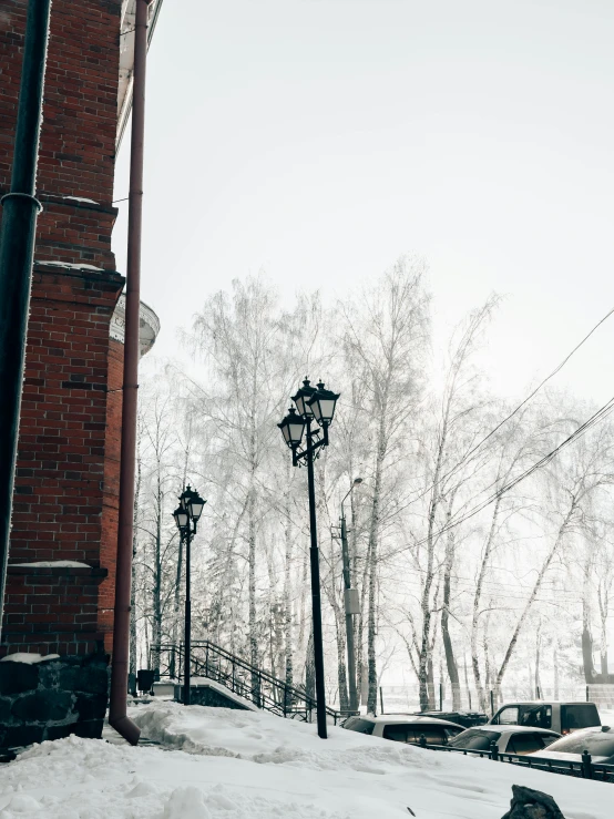 a lamppost covered in snow next to a brick building