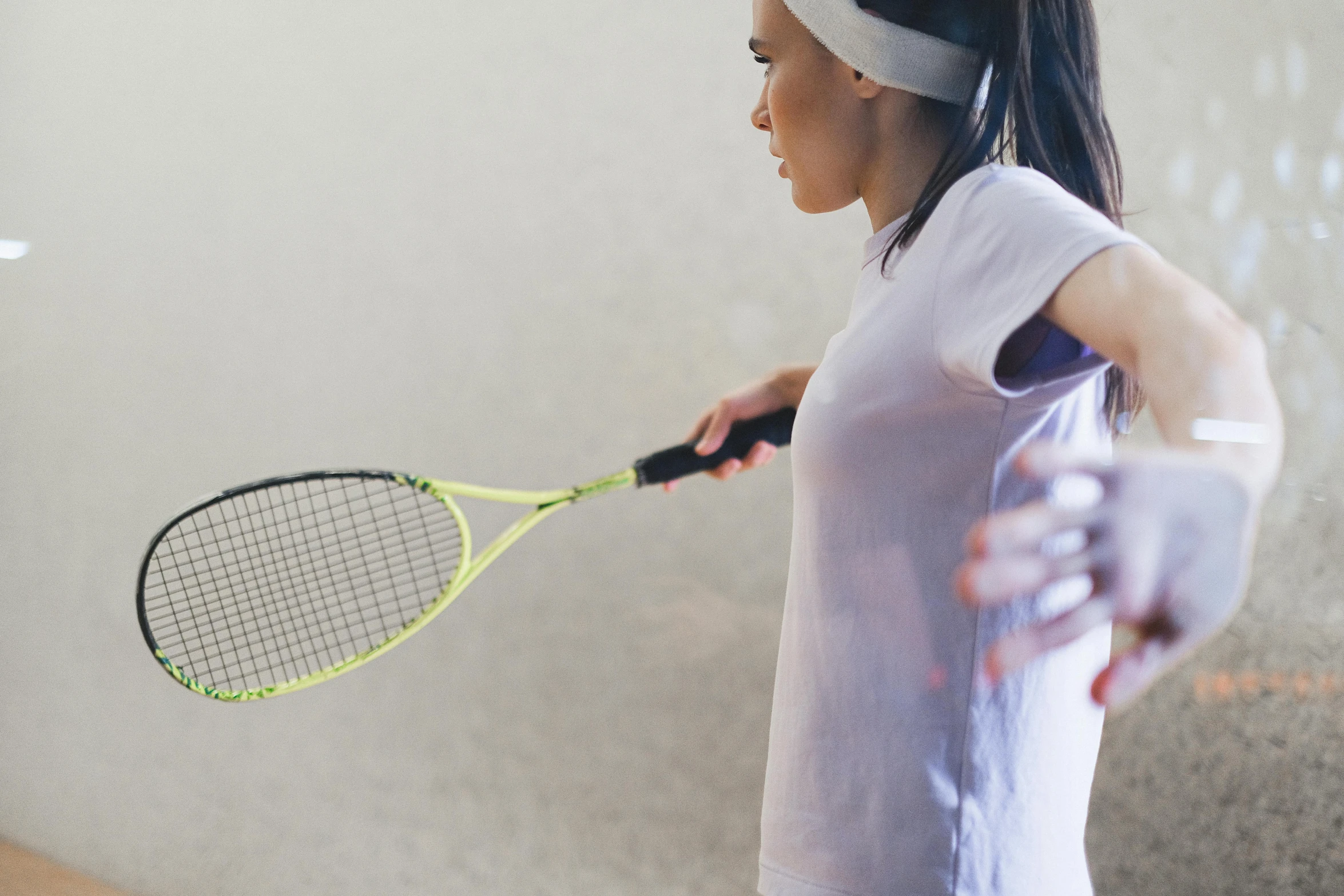 a young woman holding a tennis racket standing next to a wall