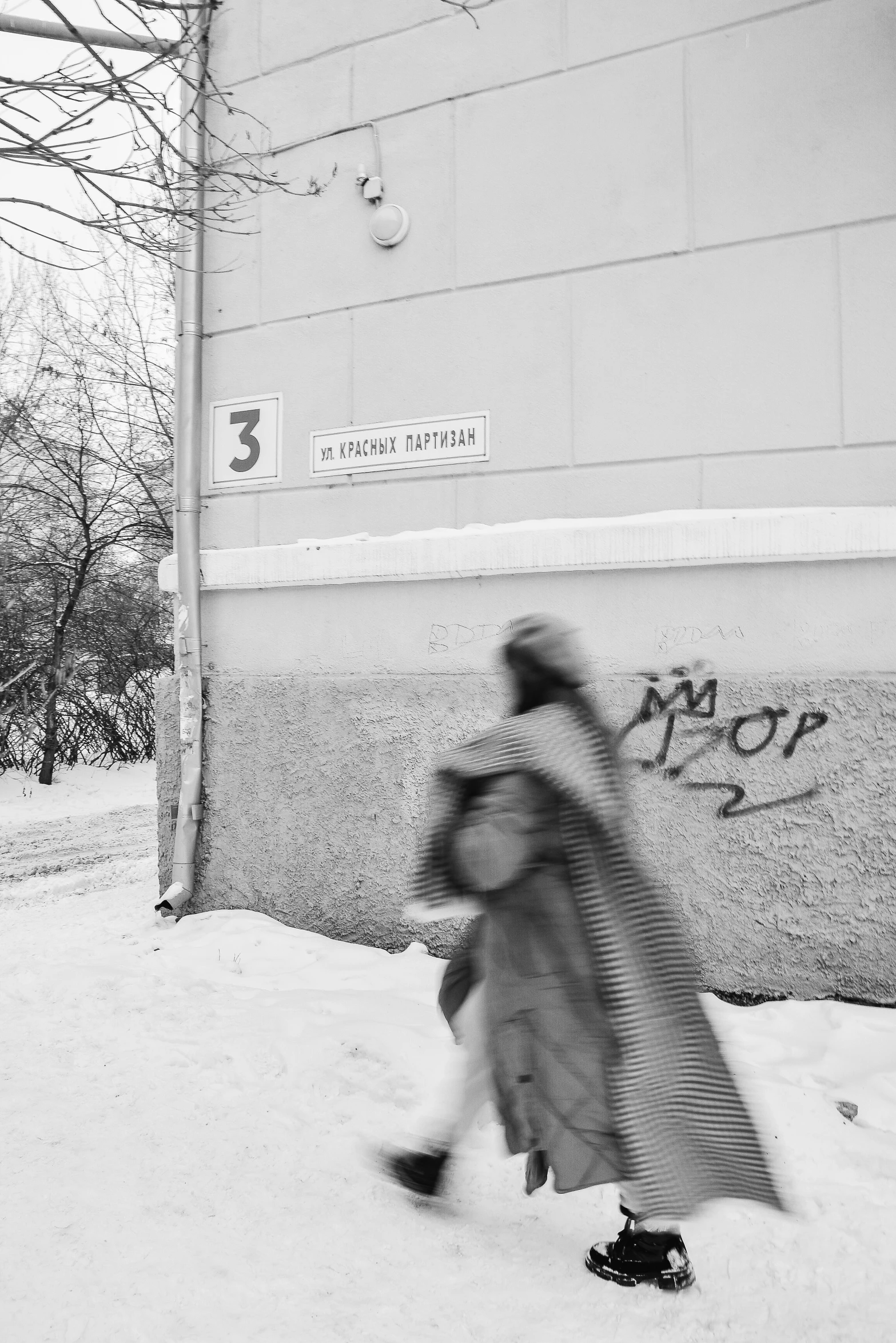 a couple walking on snow covered ground next to a building