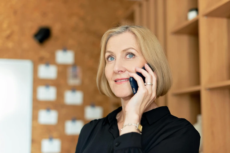 woman in black shirt holding cell phone to her ear