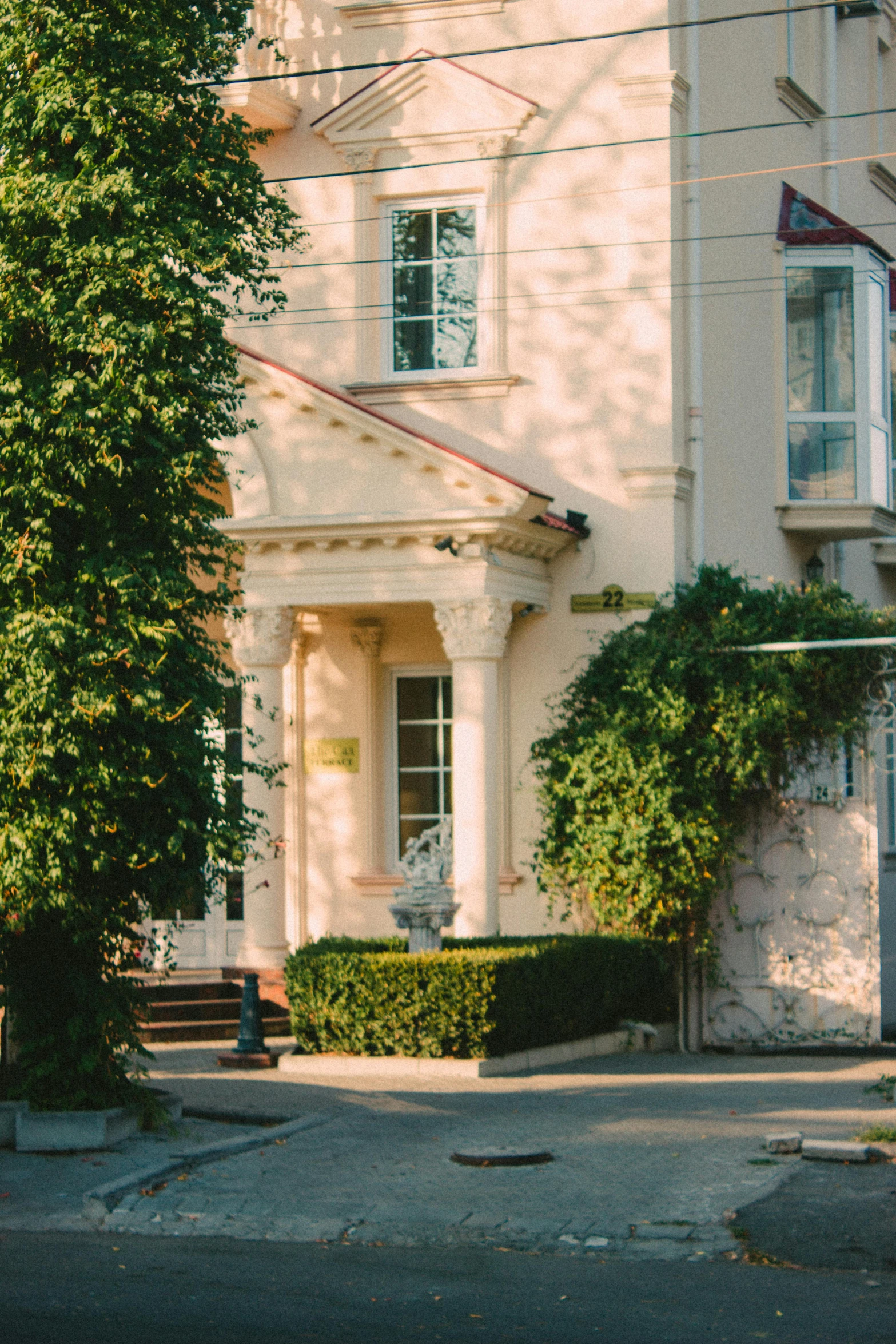 two tall houses on the corner with a large tree next to them