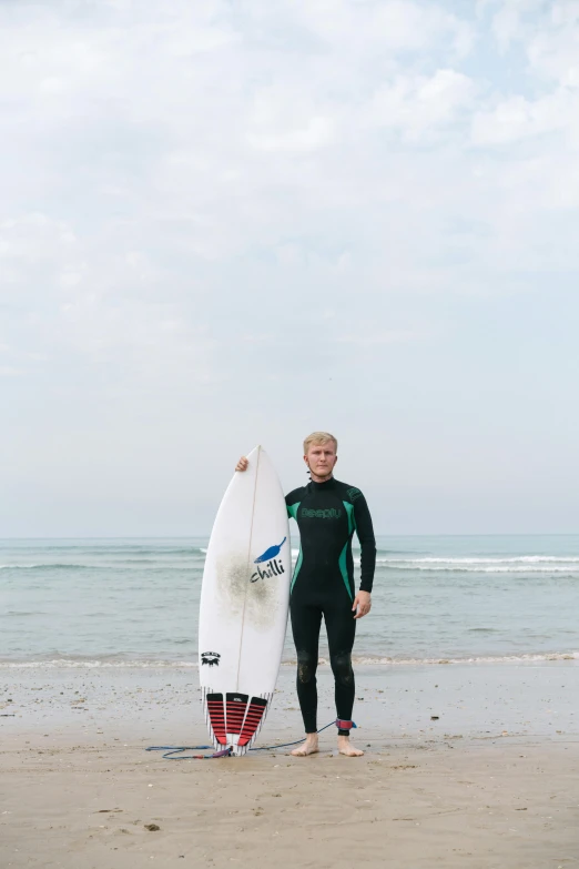 a man wearing a wet suit holding up a surfboard on the beach